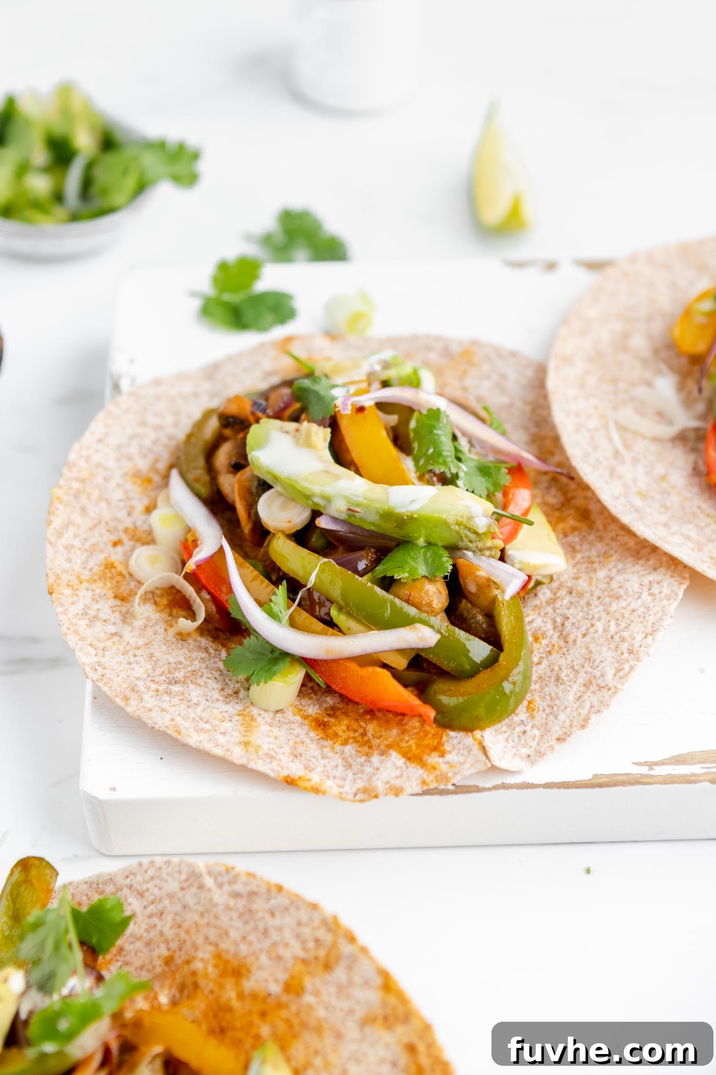 A vibrant tortilla filled with perfectly cooked bell peppers, savory onions, and creamy avocado slices, resting on a rustic wooden cutting board, ready to be enjoyed.