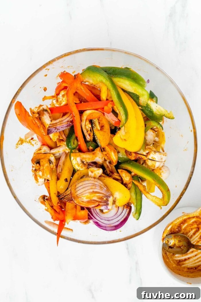 A large mixing bowl filled with vibrant, thickly sliced bell peppers, onions, and mushrooms, all glistening with a rich, savory marinade, ready for cooking.