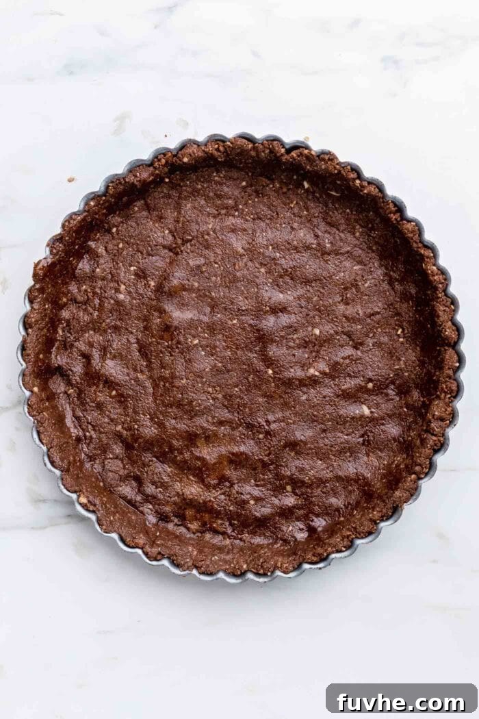 A perfectly pressed chocolate pie crust, smooth and even, snugly fitted into a pie tin, ready for the filling.