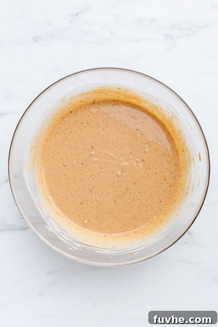 A thick, luscious peanut butter mixture, the star of the pie filling, in a large mixing bowl, showcasing its creamy texture.