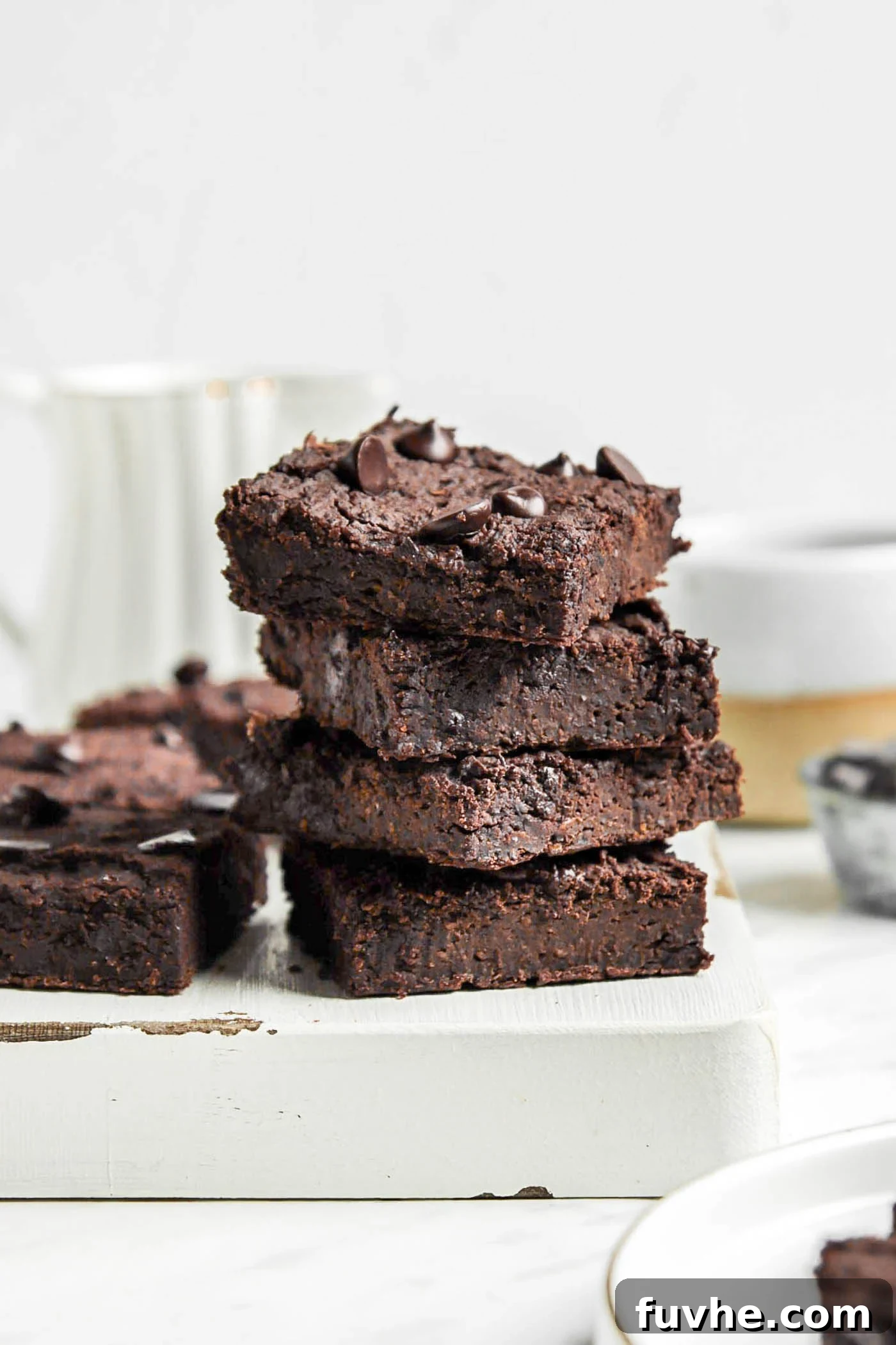 Fudgy Vegan Black Bean Brownies 2 Stack of 3 black bean brownies on a cutting board, showcasing their fudgy texture and chocolate chips.