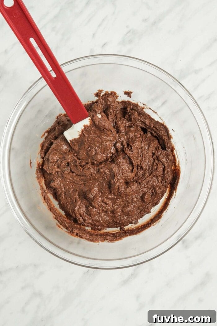 Fudgy Vegan Black Bean Brownies 5 Thick chocolate brownie batter with chocolate chips in a glass bowl, ready for baking.