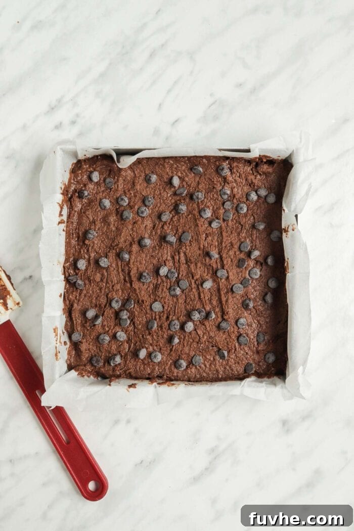 Fudgy Vegan Black Bean Brownies 6 Brownie batter sprinkled with chocolate chips in a baking pan, ready for the oven.
