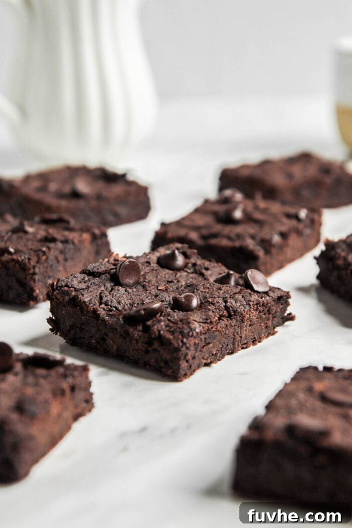Fudgy Vegan Black Bean Brownies 7 Close up of a black bean chocolate chip brownie on a marble counter top, showing its dense, moist interior.