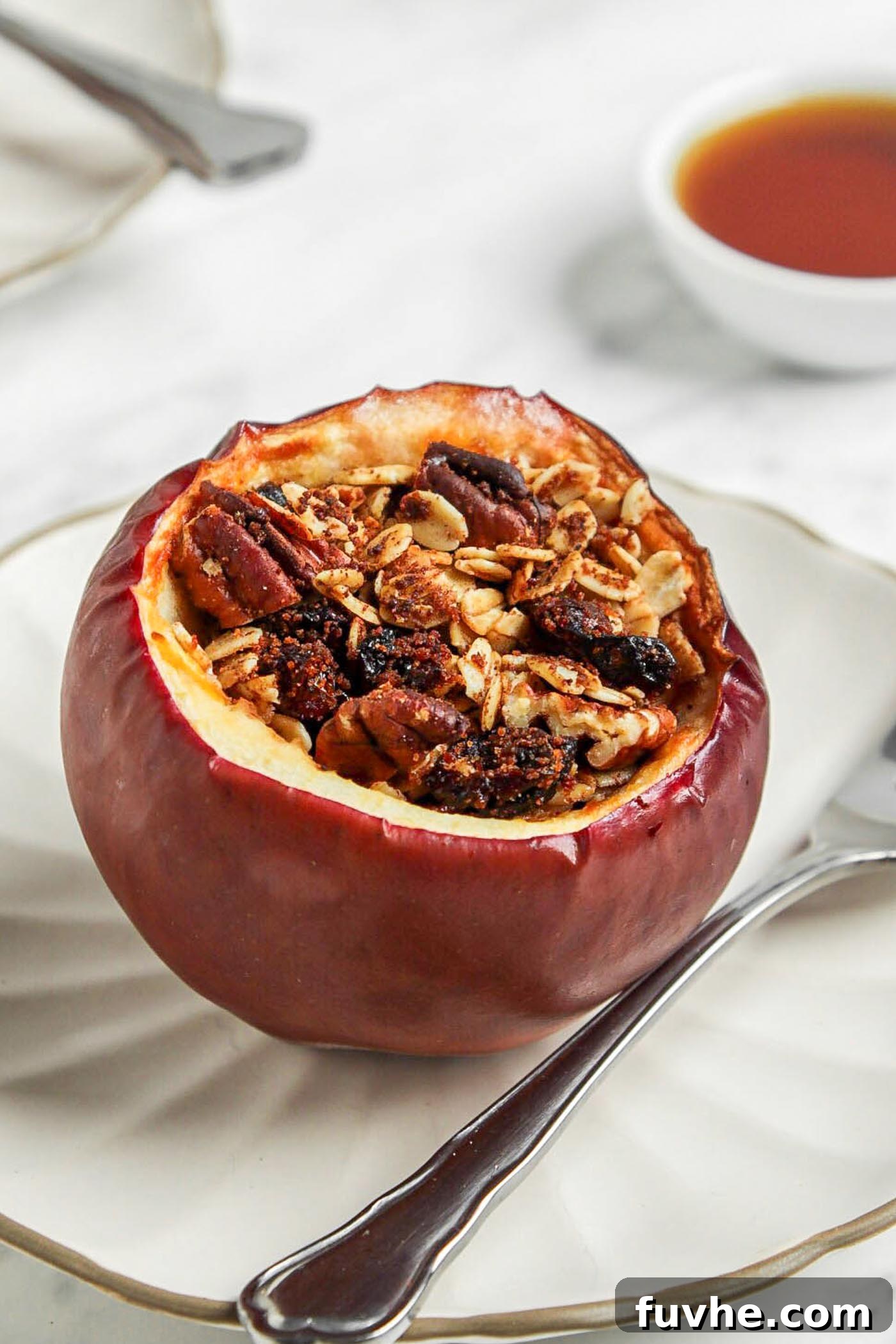 Wholesome Vegan Stuffed Apples 2 A perfectly baked stuffed apple on a small white plate, ready to be enjoyed with a spoon.