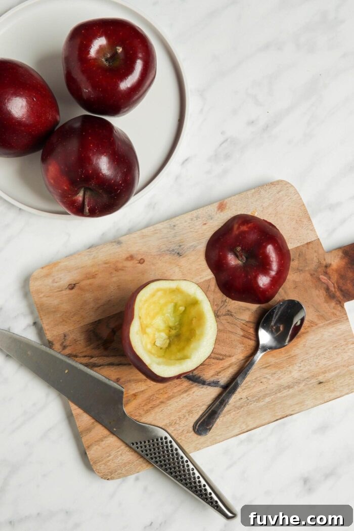 Wholesome Vegan Stuffed Apples 5 A hollowed-out apple on a cutting board, expertly cored with a spoon to create space for filling.