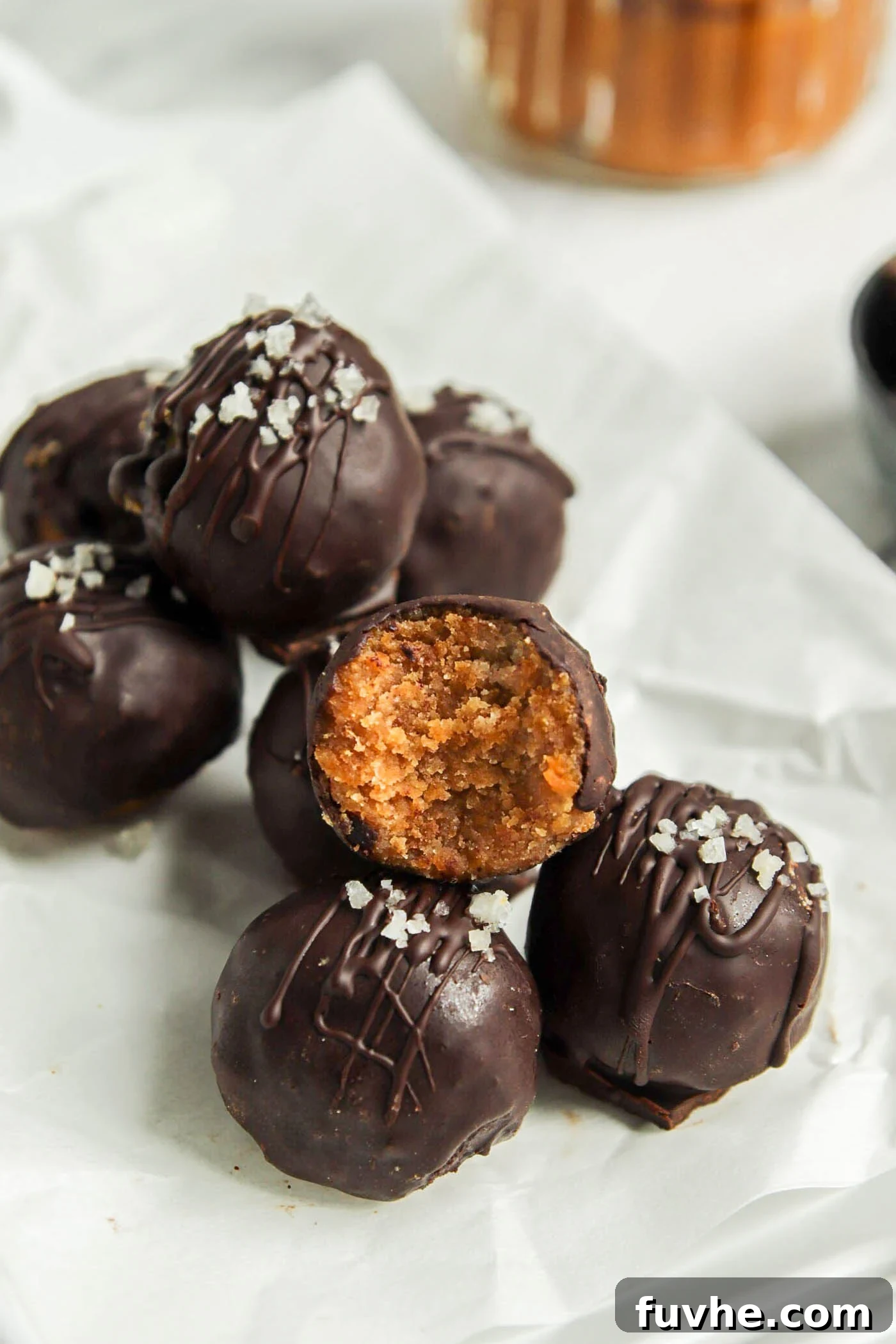 Spiced Vegan Pumpkin Chocolate Truffles 2 Stack of pumpkin truffles on a plate. One has a bite out of it showing texture inside.