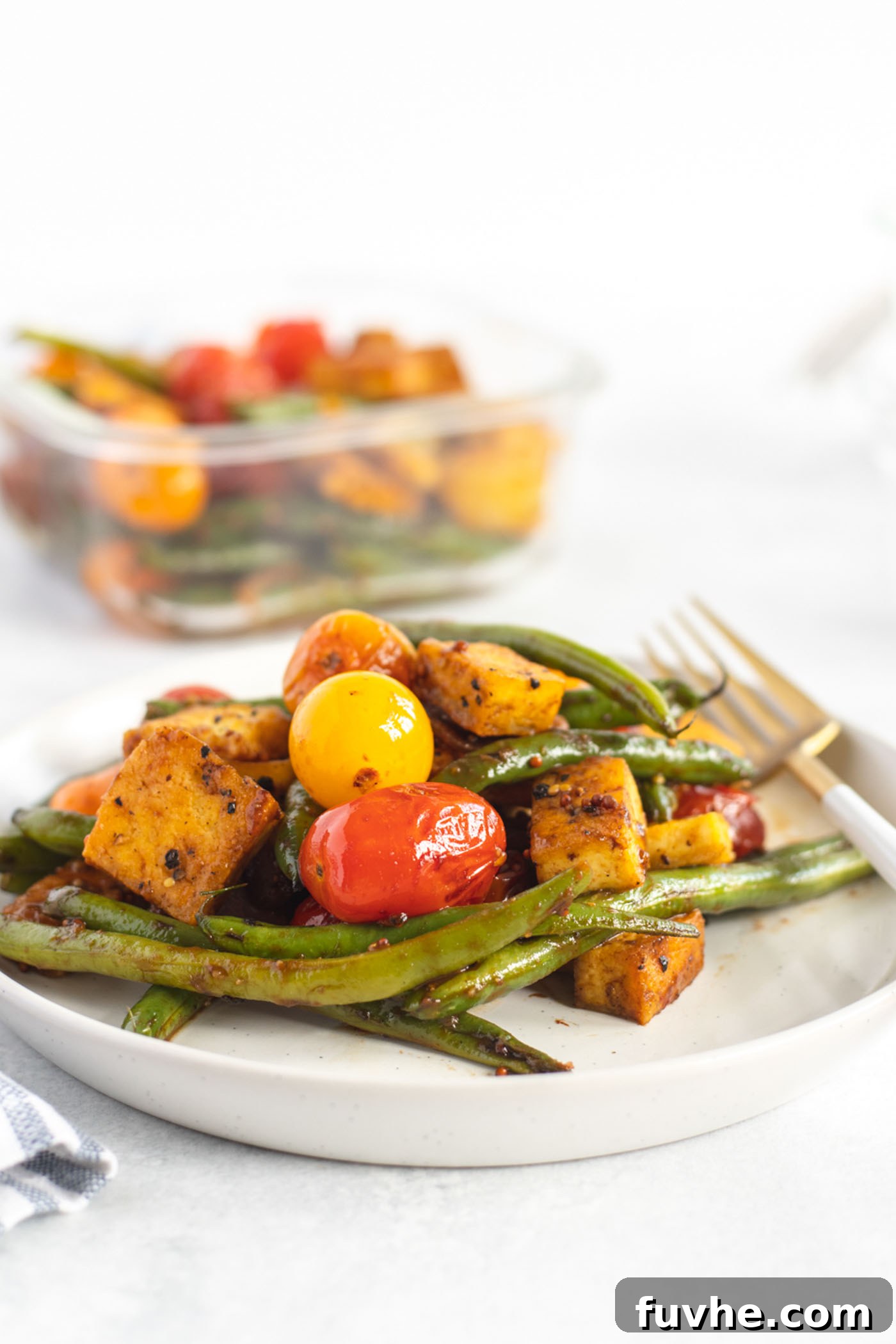 Crispy balsamic tofu with green beans and cherry tomatoes on a small plate, ready to be enjoyed.