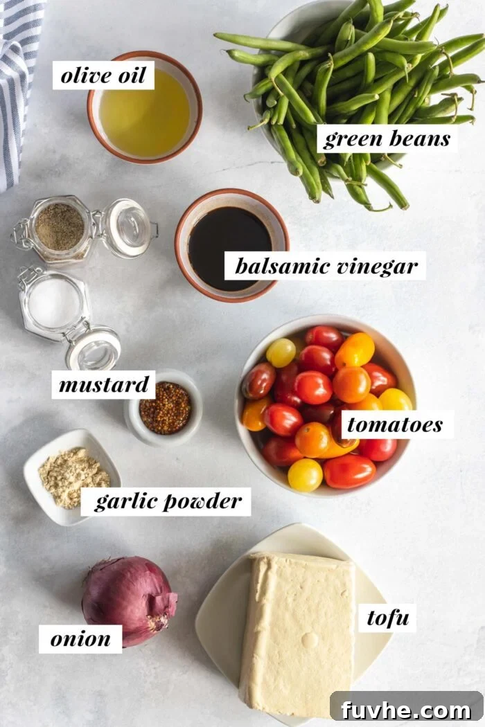 A visual display of fresh ingredients laid out on a wooden board, including a block of tofu, green beans, cherry tomatoes, and onions, all ready for making balsamic tofu and vegetables.