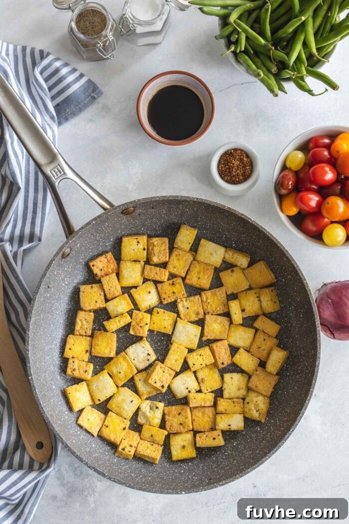 Cubed tofu browning in a hot skillet, becoming golden and crispy.