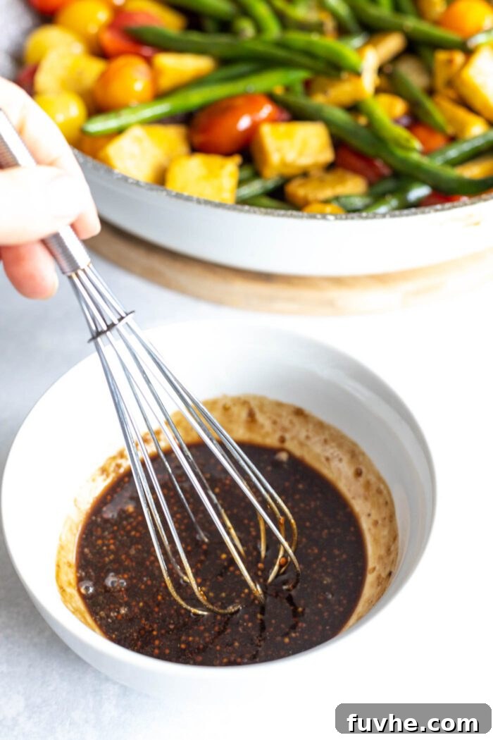 A whisk stirring together the ingredients for the balsamic sauce in a small mixing bowl.