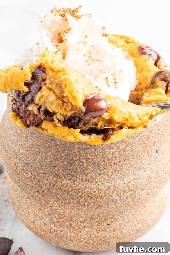 Spoon lifting a spoonful of pumpkin mug cake out of a mug.