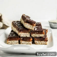 Stack of 6 homemade Twix-style bars with a shortbread, caramel and chocolate layer on a small dish.
