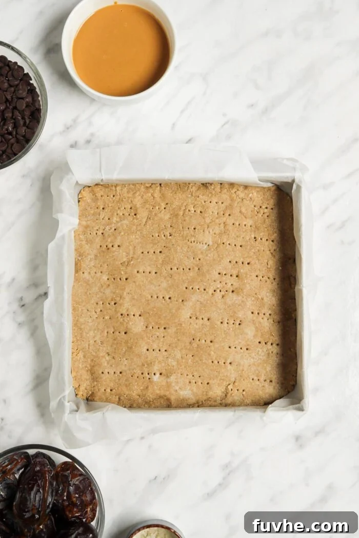 Baked shortbread crust in a baking pan lined with parchment paper.