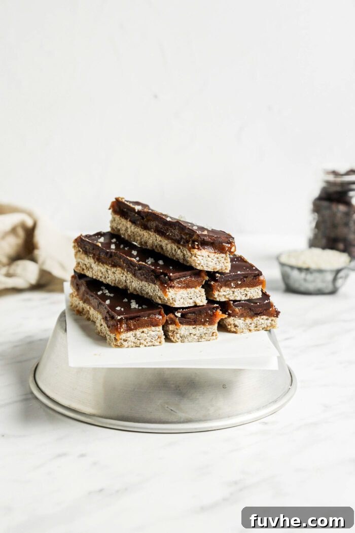 Stack of 6 homemade Twix candy bars on an upside down metal bowl lined with parchment paper.