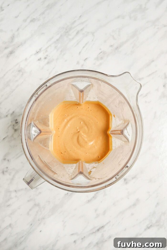 Creamy cashew-based dip blended in a large blender container, ready for artichokes.