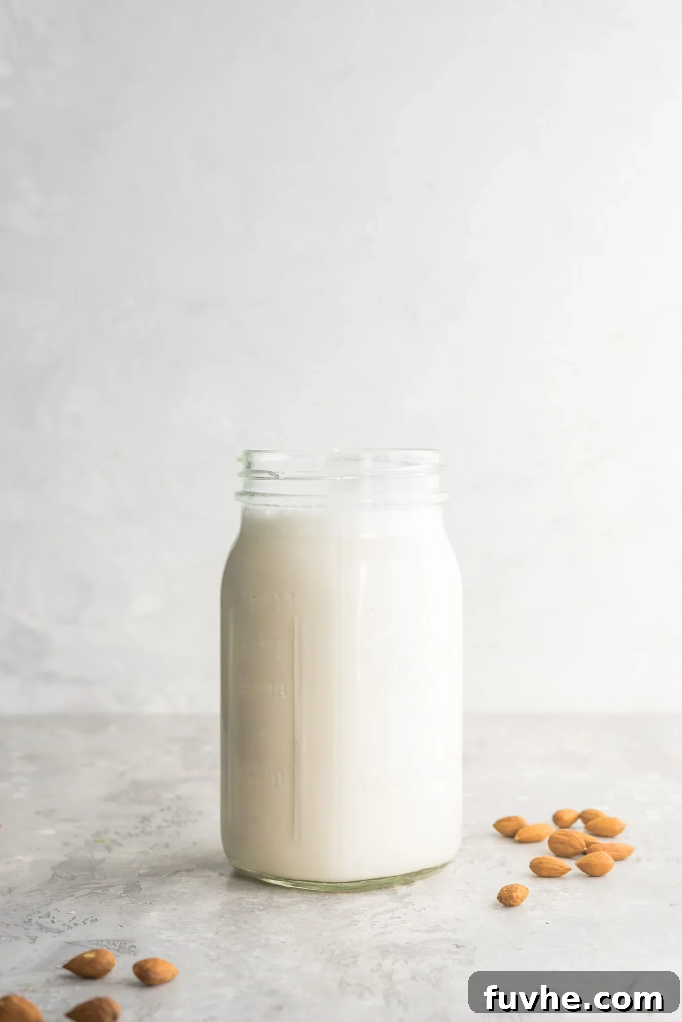 Easy Homemade Almond Milk in a Mason Jar with Almonds Scattered Around