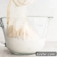 A glass jar of homemade almond milk with a nut milk bag in it.