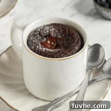 Mugful of Vegan Chocolate Bliss 8 Chocolate mug cake on a small plate with 2 spoons resting on plate.