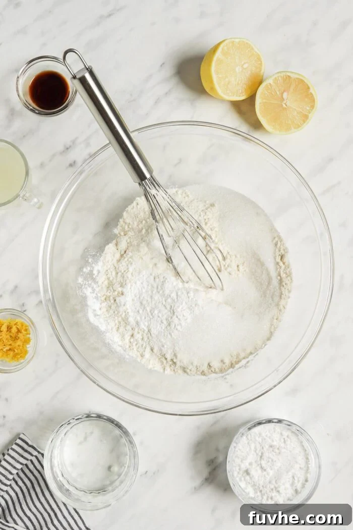 Zesty Vegan Lemon Loaf 4 Dry baking ingredients being mixed together in a glass mixing bowl with a whisk.