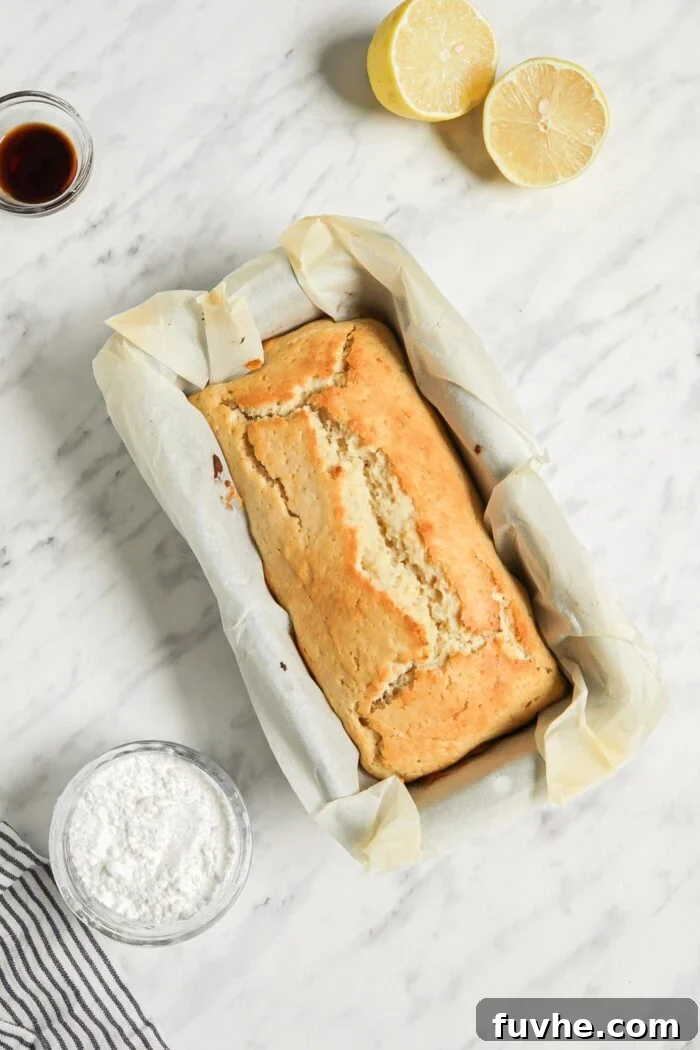 Zesty Vegan Lemon Loaf 6 Baked lemon bread in a loaf pan lined with parchment paper.