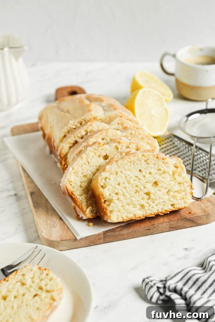 Zesty Vegan Lemon Loaf 7 Sliced lemon loaf with icing on a cutting board.