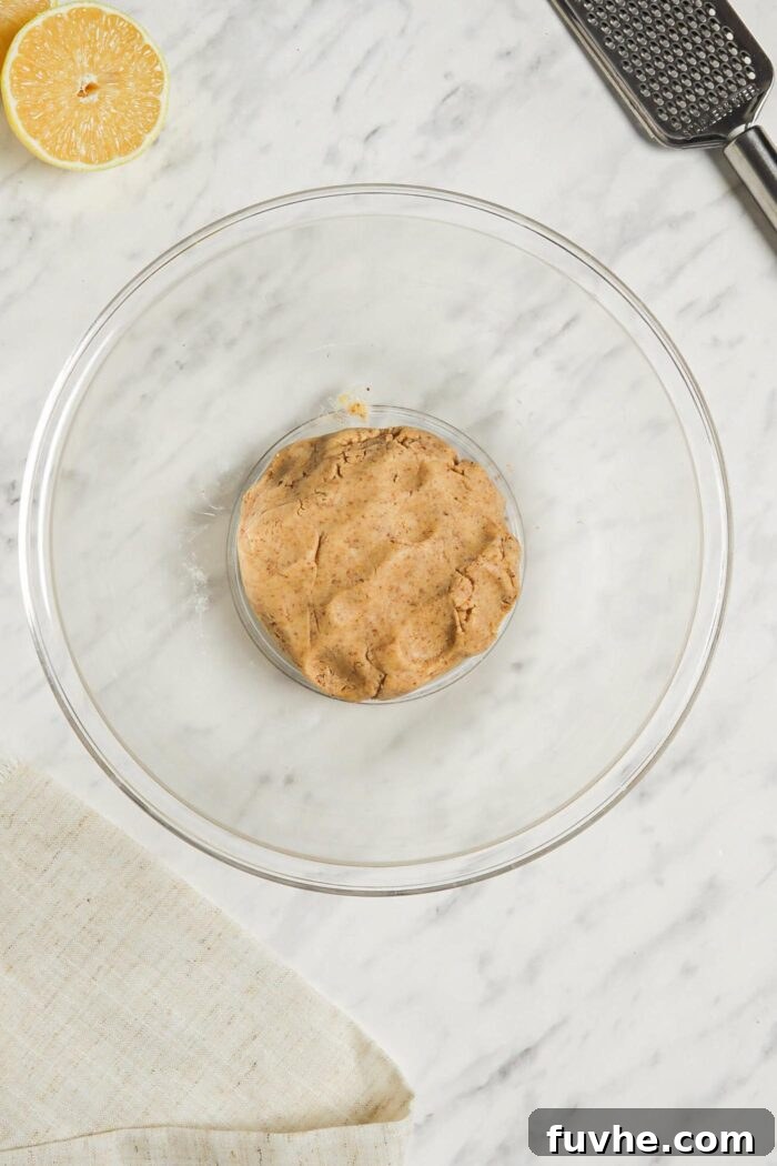 A ball of raw shortbread dough resting in a clear glass mixing bowl, perfectly formed and ready to be pressed into a pan.