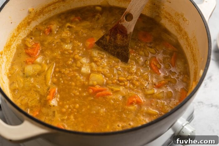 Zesty Lemon Lentil Comfort 6 Lemon red lentil soup with tender carrots gently simmers in a large soup pot, creating a rich and aromatic broth.