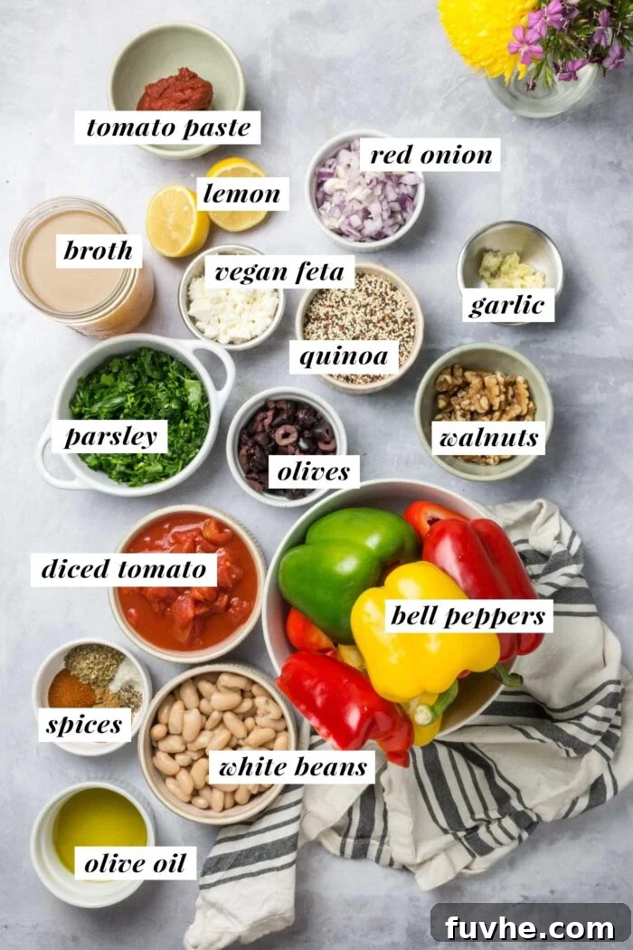 A visual spread of fresh ingredients including bell peppers, quinoa, cannellini beans, olives, garlic, lemon, parsley, and spices, laid out for Mediterranean stuffed peppers.