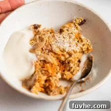 Bowl of carrot cake baked oatmeal topped with yogurt and almond butter.