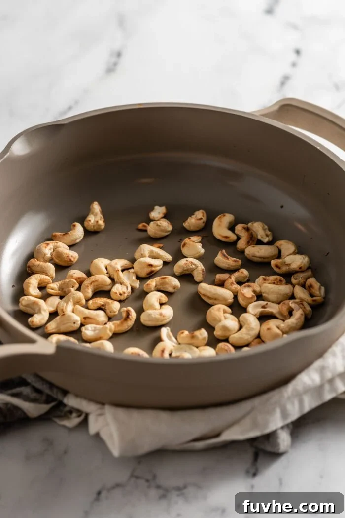 Raw cashews toasting in a skillet.