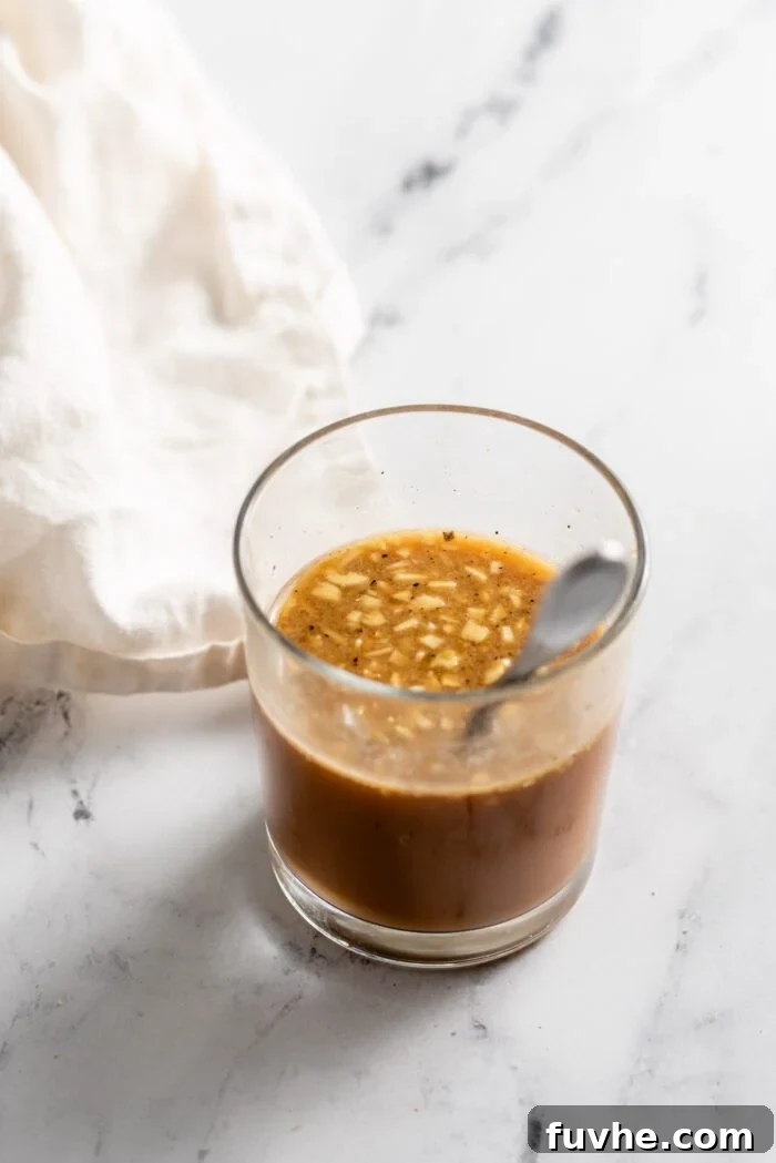 Jar of stir fry sauce with garlic with a spoon resting in the jar.