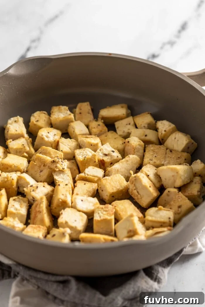 Browned cubes of tofu frying in a skillet.