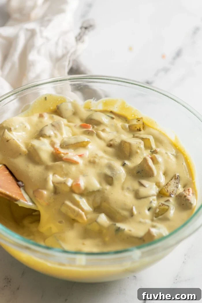 A thick, rich omelette and vegetable batter, a harmonious blend of textures and colors, resting in a clear glass mixing bowl, perfectly combined and ready for baking.