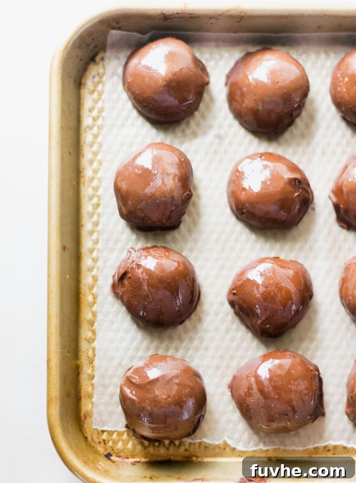No-Bake Vegan Peanut Butter Chocolate Truffles 3 Eight perfectly coated vegan chocolate peanut butter balls arranged on a small baking sheet lined with parchment paper, ready to set.