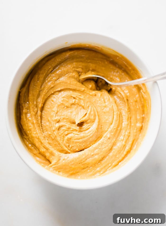 No-Bake Vegan Peanut Butter Chocolate Truffles 7 A creamy, well-combined peanut butter mixture in a bowl, with a spoon resting, showing the perfect consistency before rolling.