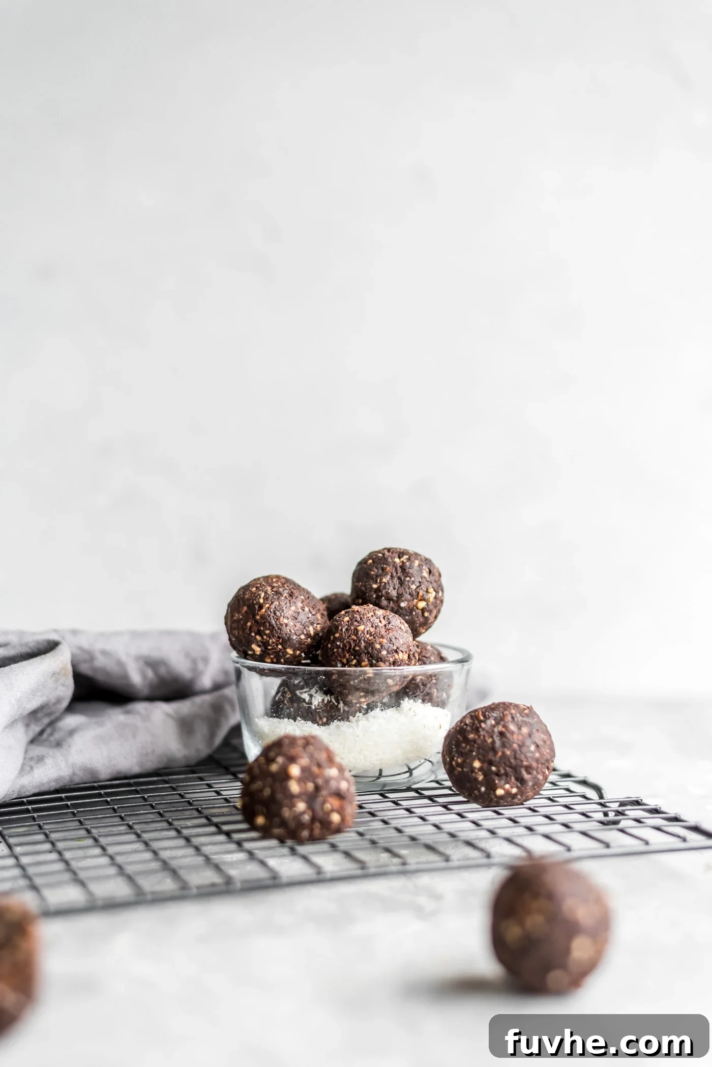 Chocolate Coconut Recharge Bites 2 Some no-bake chocolate cashew coconut balls in a glass dish sitting on a cooling rack.
