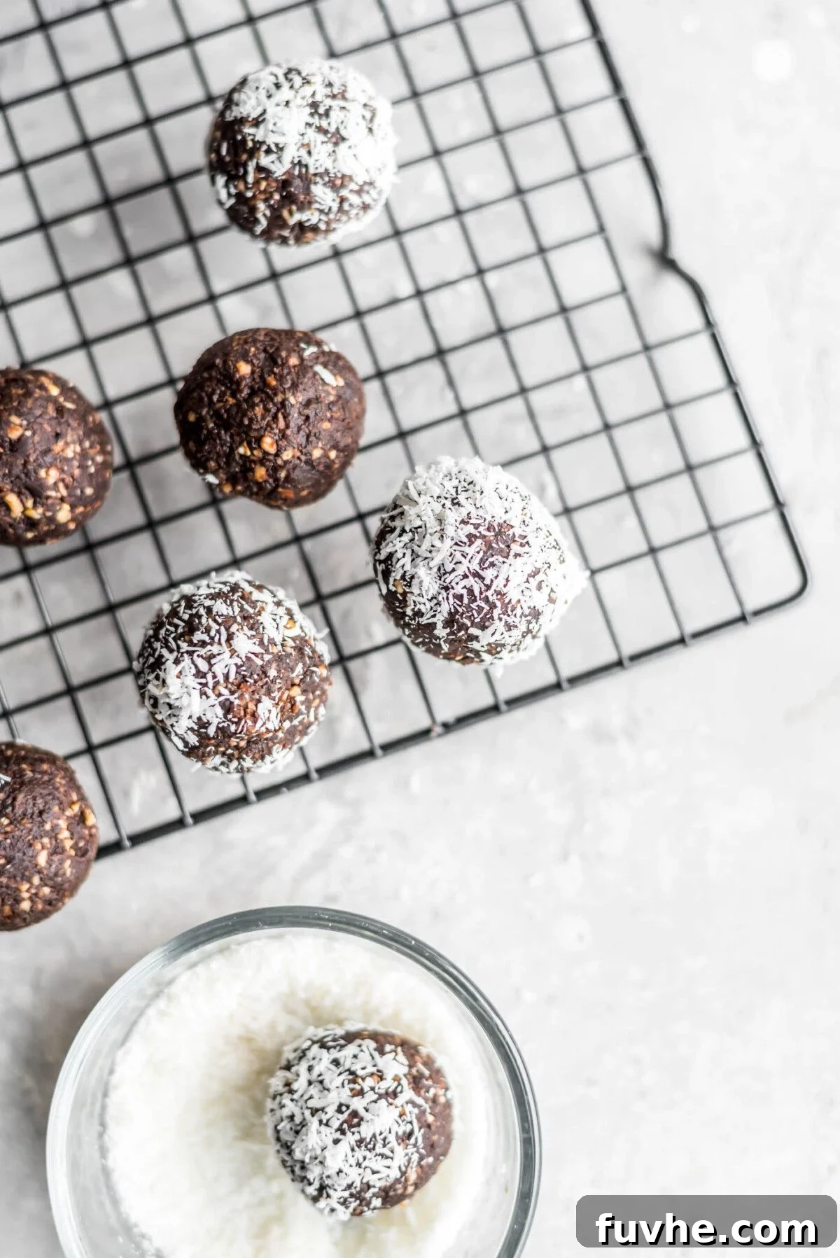 Chocolate Coconut Recharge Bites 4 A few chocolate energy balls on a black wire cooling rack.