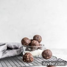 Vegan no-bake chocolate cashew coconut balls in a glass dish sitting on a cooling rack.