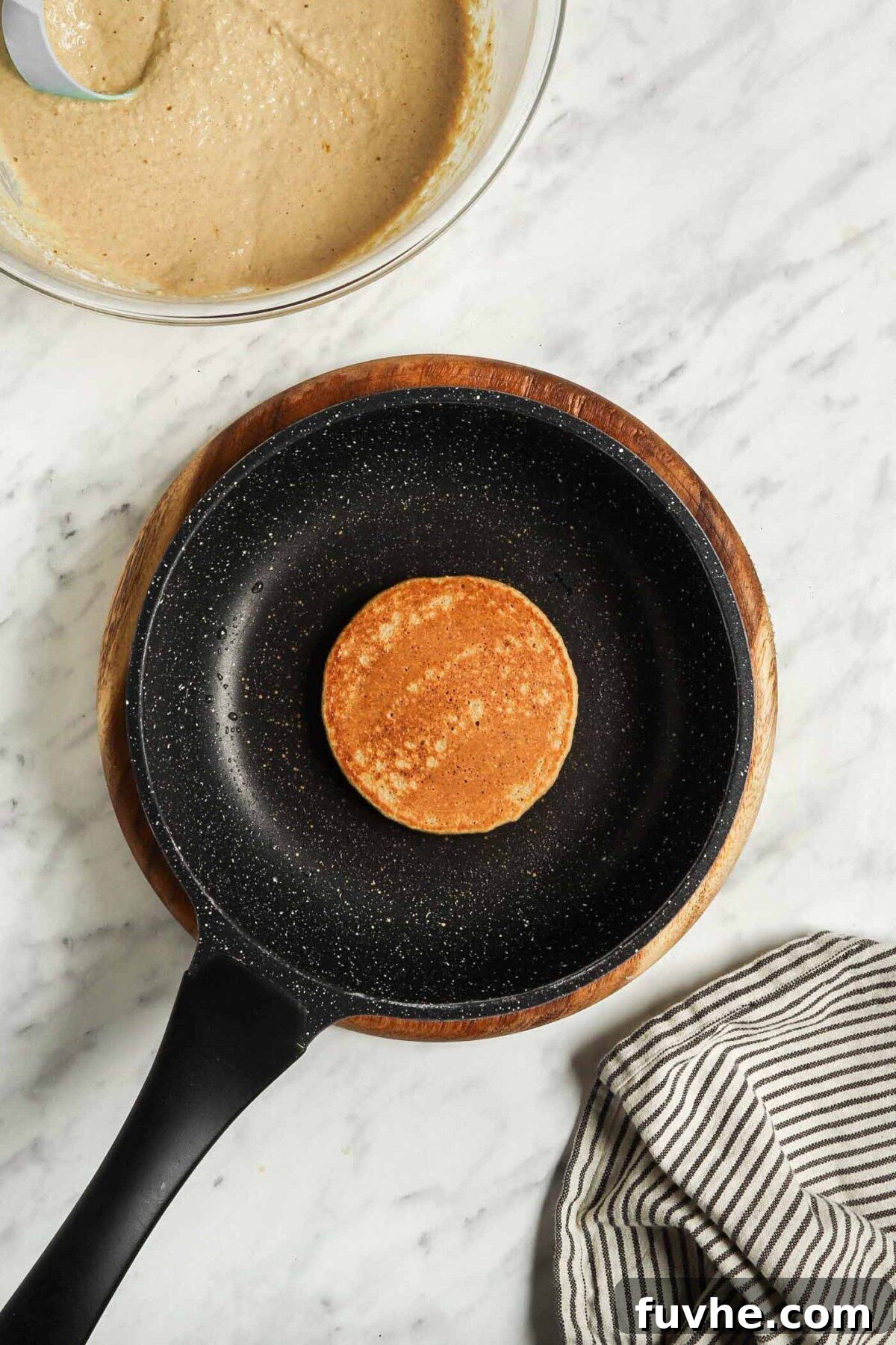 A cooked, small brown pancake in a small skillet.