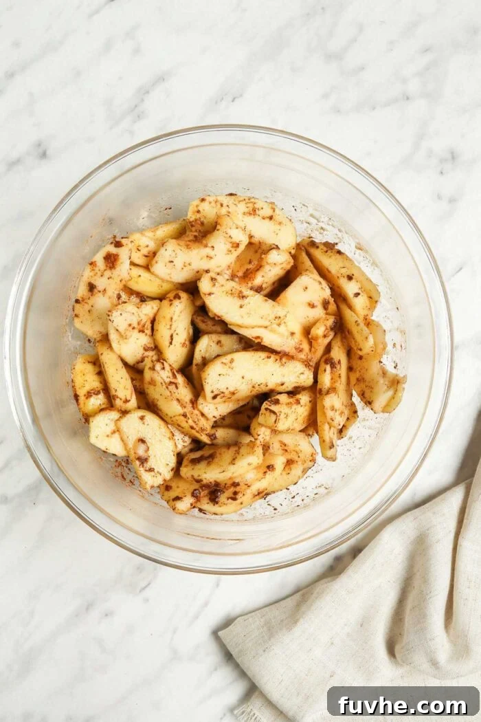 Sliced apples coated in cinnamon in a bowl.
