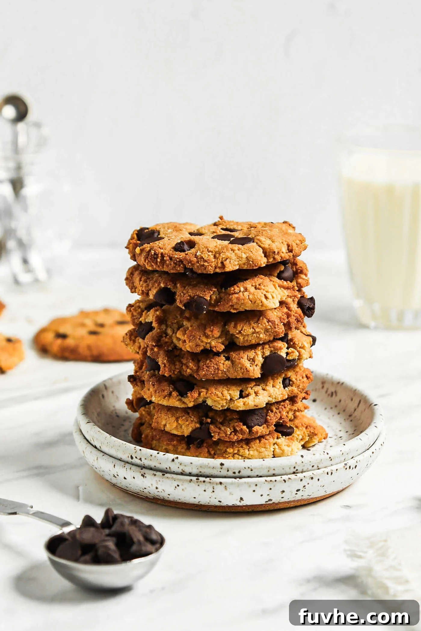 Stack of almond flour chocolate chip cookies on a small plate with a glass of milk in the background.