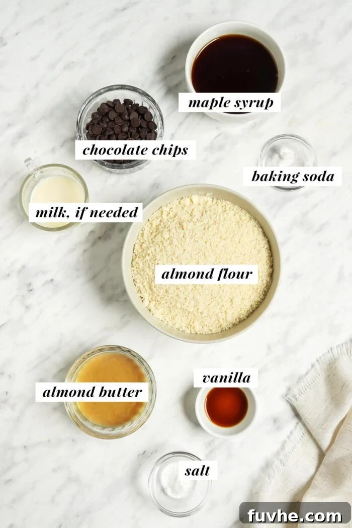 All the ingredients needed for making an almond flour chocolate chip cookie recipe in small bowls on a marble surface.