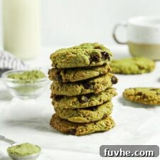 Sublime Vegan Matcha Cookies 8 Stack of almond flour matcha chocolate chip cookies. There's a glass of milk in the background and a tablespoon of matcha powder in the foreground.