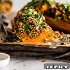 Sliced rice, lentil and kale stuffed butternut squash on a parchment paper-lined baking tray.