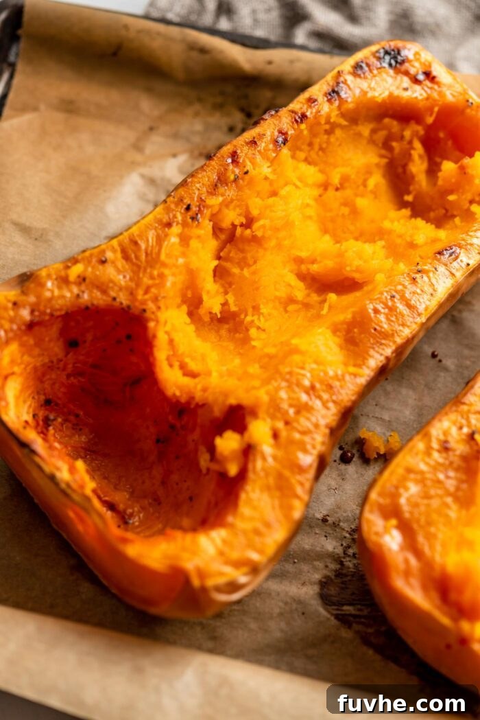 Comforting Vegan Stuffed Butternut Squash 7 One half of a cooked butternut squash on a roasting pan, with a portion of its flesh carefully scooped out to create more space for the stuffing.