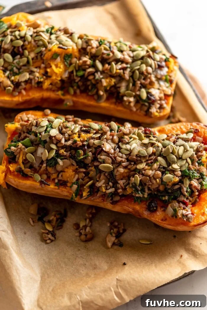 Comforting Vegan Stuffed Butternut Squash 9 Two halves of golden-brown roasted butternut squash, generously filled with the savory rice and lentil stuffing, resting on a roasting pan.