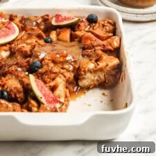 Vegan baked french toast casserole with a slice out of it. Small jar of caramel sauce in the background.