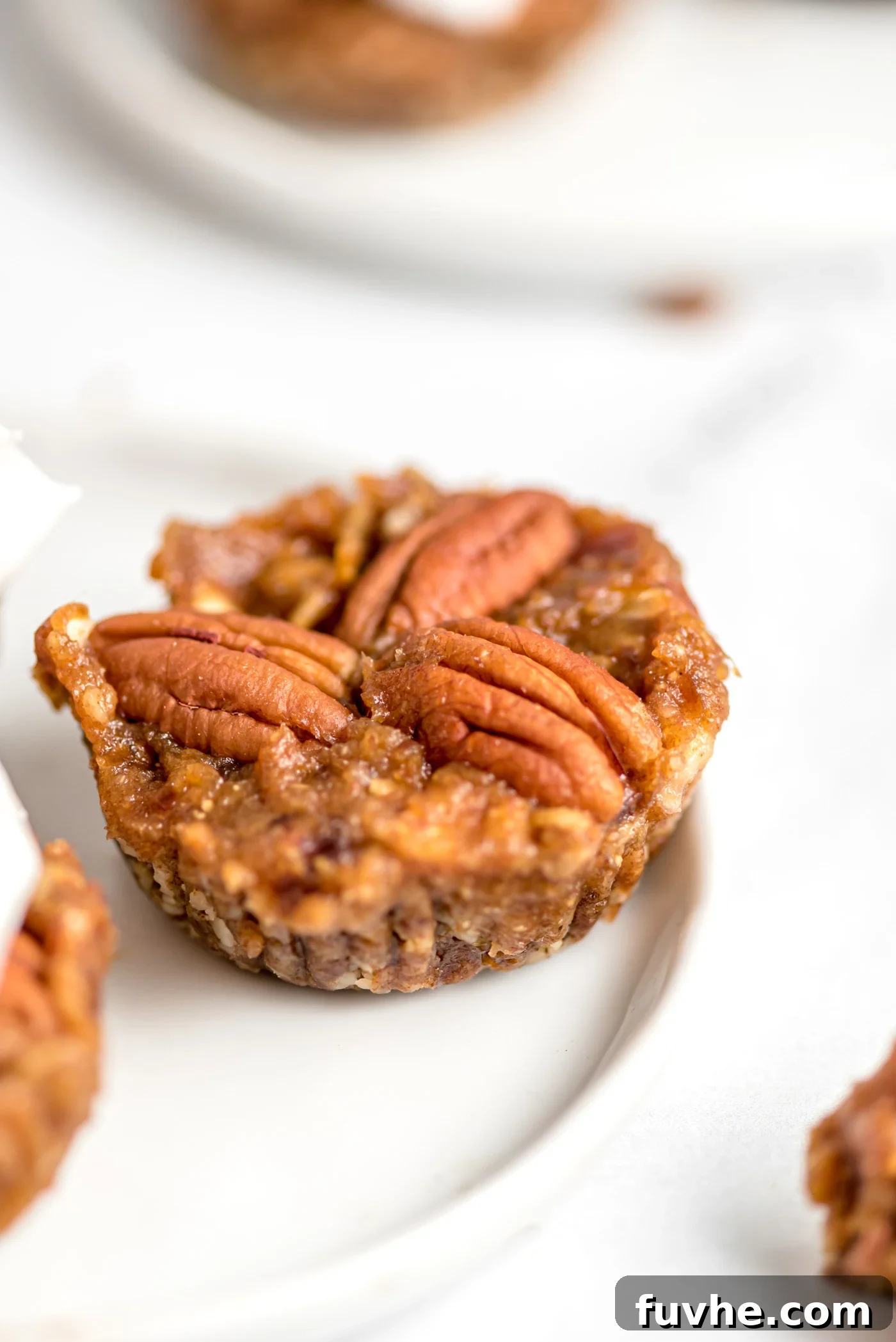 Quick and Easy No-Bake Pecan Tartlets 2 Mini no-bake pecan pie tart topped with 3 pecans on a small plate.