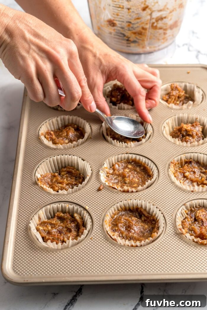 Quick and Easy No-Bake Pecan Tartlets 7 Using a spoon to smooth pecan pie filling in mini tarts made in a muffin pan.